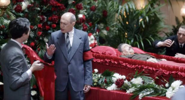 Die Aufbahrung von Josef Stalin, umgeben von Trauergästen und Blumen.