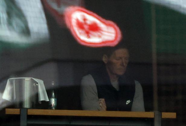 Ein Mann mit verschränkten Armen sitzt während des Bundesligaspiels Eintracht Frankfurt gegen Mainz 05.