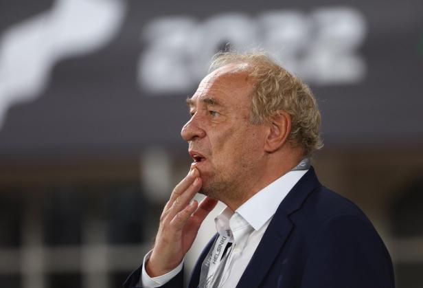 Ein Mann im Anzug mit einem „Helsinki“-Lanyard berührt sein Kinn.