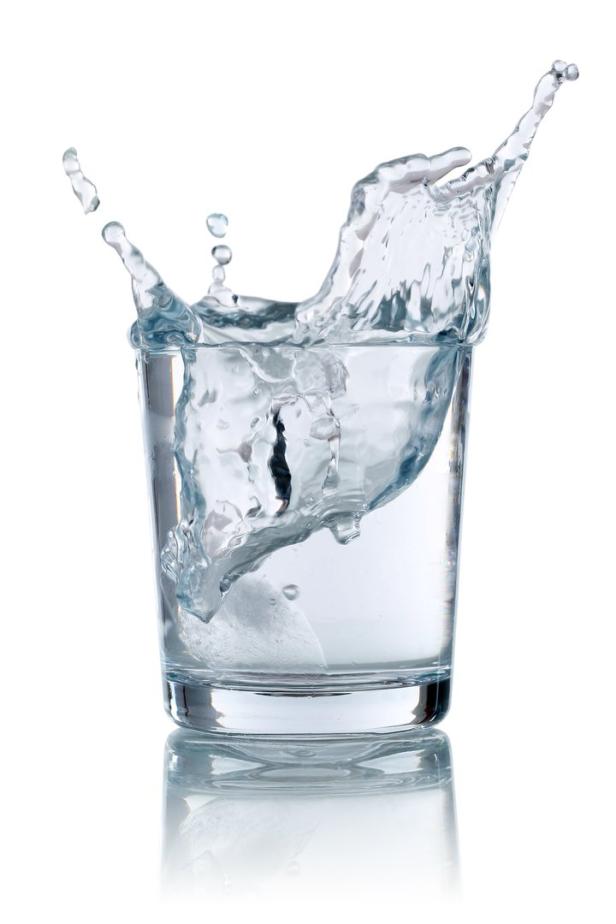 Ein Eiswürfel fällt in ein Glas Wasser und erzeugt eine spritzende Bewegung.