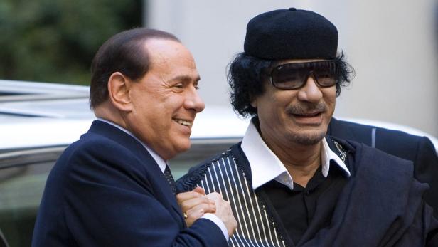 Silvio Berlusconi schüttelt Muammar al-Gaddafi die Hand.