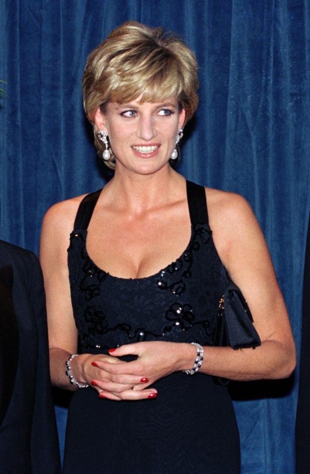 Prinzessin Diana in einem schwarzen Kleid mit Schmuck und einer kleinen Handtasche.