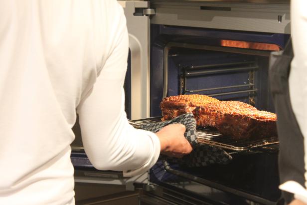 Eine Person holt einen Braten aus dem Ofen.