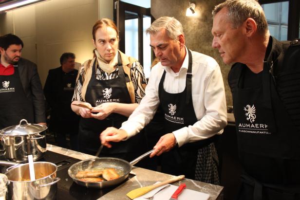 Mehrere Personen kochen gemeinsam in einer Küche mit Aumaerk-Schürzen.