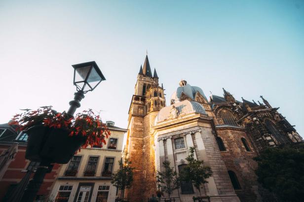 Die Aachener Kathedrale und ein Gebäude mit einer Straßenlaterne im Vordergrund.
