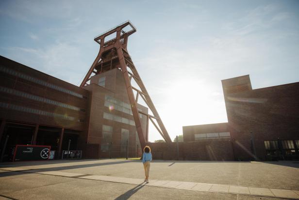 Eine Frau geht auf das Gelände der Zeche Zollverein in Essen zu.