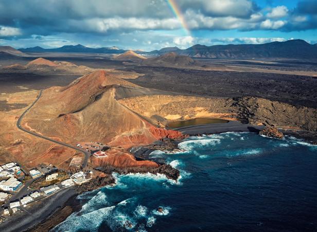 Luftaufnahme der Küstenlandschaft von Lanzarote mit einem Regenbogen am Himmel.