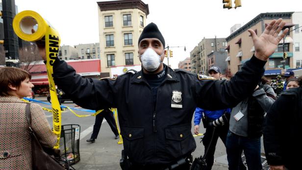 Ein New Yorker Polizist mit Maske hält Absperrband mit der Aufschrift „Scene“.