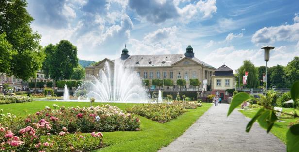 Ein Springbrunnen sprüht vor dem Kurhaus Baden-Baden in einem Rosengarten.