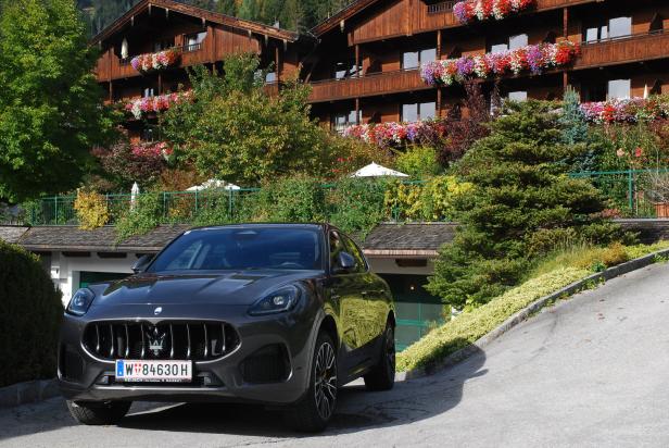 Ein grauer Maserati steht vor einem mit Blumen geschmückten Holzhaus.
