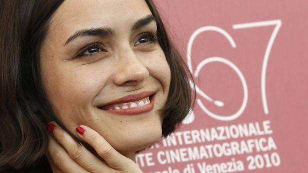Eine lächelnde Frau mit roten Nägeln vor dem Hintergrund der Internationalen Filmfestspiele von Venedig 2010.