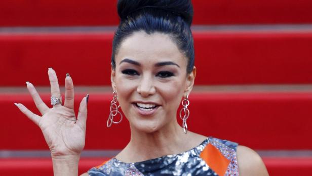 Michelle Rodriguez winkt auf einem roten Teppich.