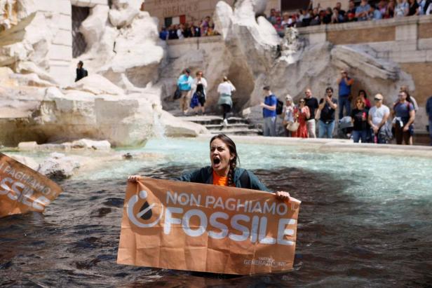 Climate activist holds banner in Trevi Fountain, Rome