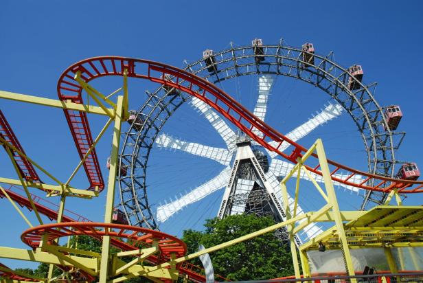 Eine Achterbahn schlängelt sich vor dem Wiener Riesenrad.