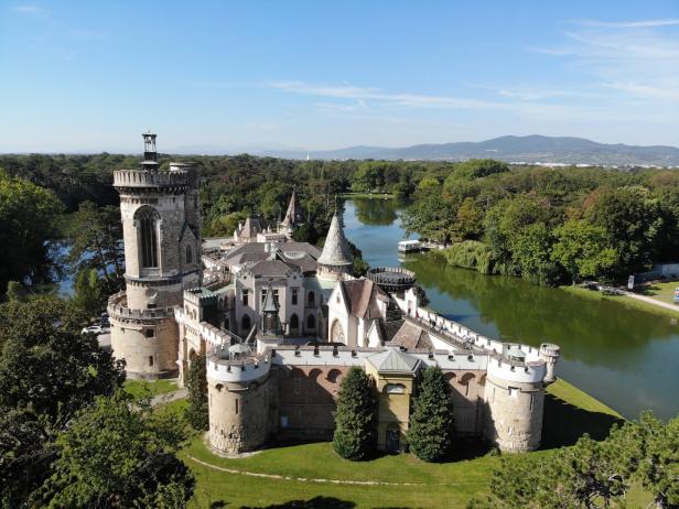 Luftaufnahme von Schloss Laxenburg, umgeben von einem See und grünen Bäumen.