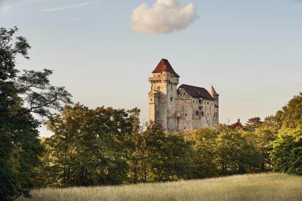 Burg Kreuzenstein thront über einer grünen Hügellandschaft.