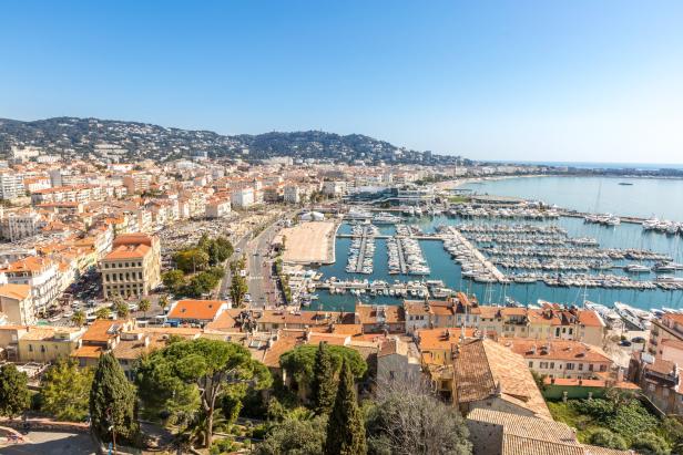 Ein Blick über Cannes mit dem Hafen voller Yachten und dem Stadtbild im Hintergrund.