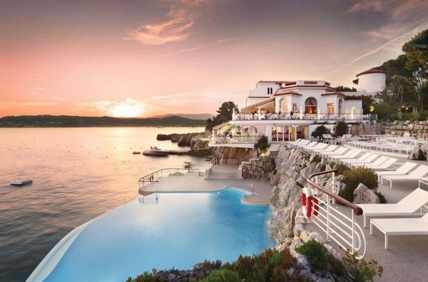 Ein Hotelresort mit Infinity-Pool an einer Klippe bei Sonnenuntergang.