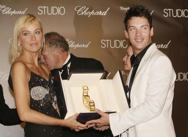 Sharon Stone und ein Mann präsentieren eine goldene Chopard-Trophäe.