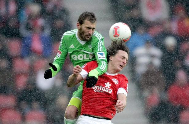 Zwei Fußballspieler kämpfen bei einem Fußballspiel im Regen um den Ball.