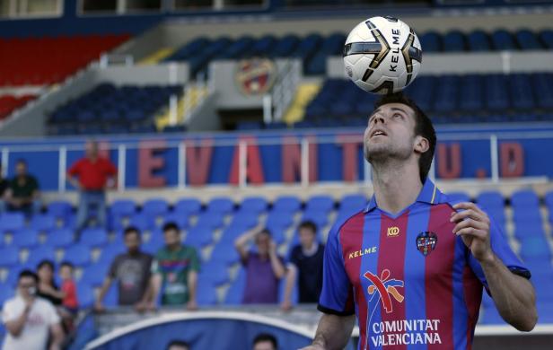 Ein Fußballspieler balanciert einen Ball auf dem Kopf im Stadion.