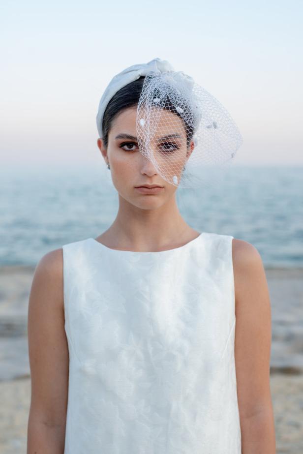 Eine Frau mit weißem Kleid und Schleier vor dem Hintergrund des Meeres.