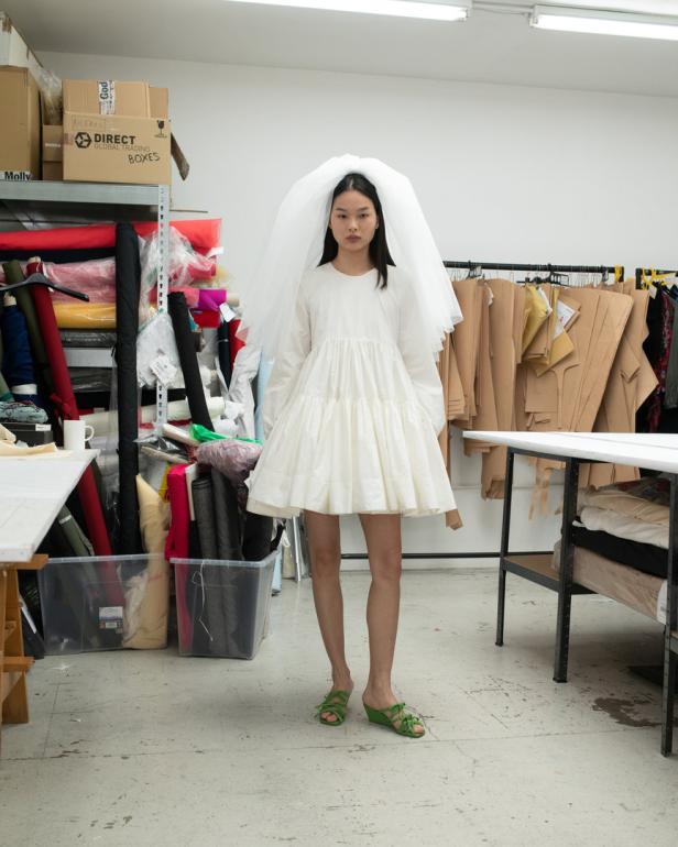 Eine Frau in einem weißen Kleid und Schleier, posiert in einem Atelier.