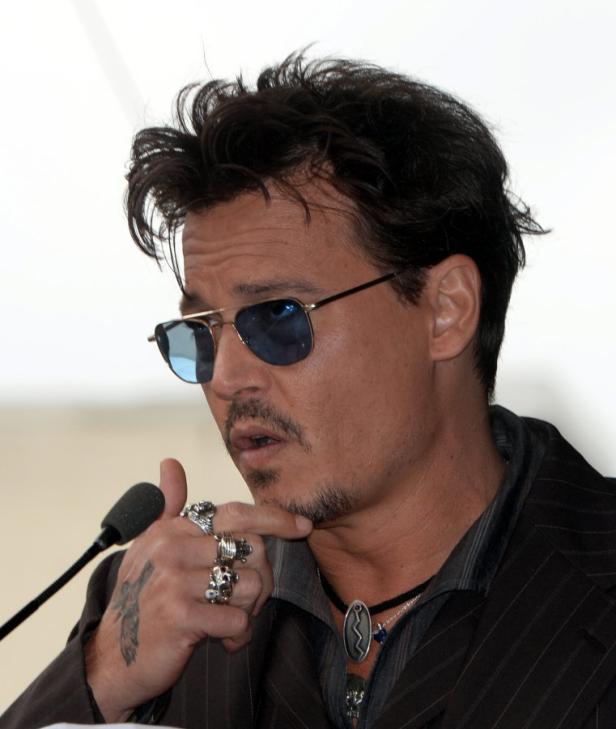 Johnny Depp spricht bei einer Veranstaltung in ein Mikrofon.