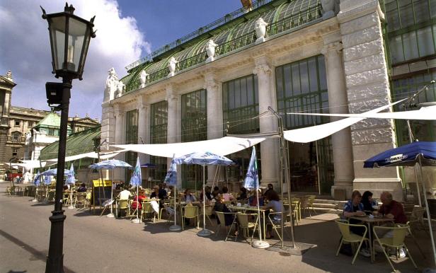 Menschen sitzen im Sommer in einem Strassencafé vor der Hofburg in Wien.