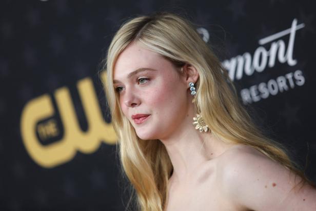 Elle Fanning mit blonden Haaren und auffälligen Ohrringen auf einem Event.