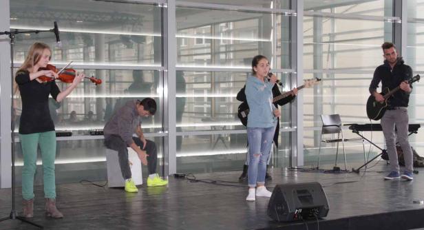 Eine Band spielt auf einer Bühne mit Geige, Gitarre, Bass und Cajón.