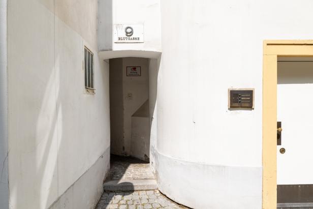 Ein Blick in die Blutgasse 9, gekennzeichnet durch weiße Wände und Kopfsteinpflaster.