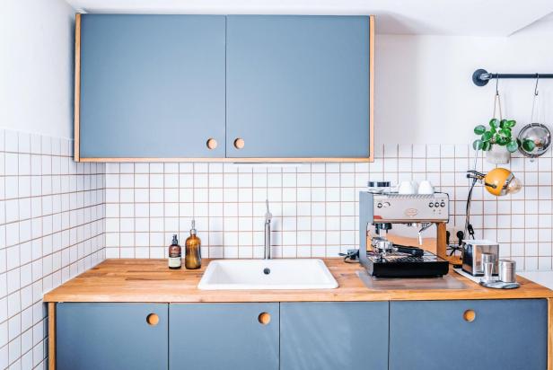 Eine moderne Küche mit blauen Schränken, einer hölzernen Arbeitsplatte und einer Espressomaschine.
