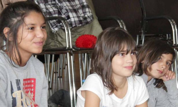 Drei junge Mädchen sitzen nebeneinander und schauen in die Ferne.