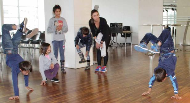 Eine Gruppe von Kindern und eine Frau in einem Raum, zwei Jungen machen Handstände.