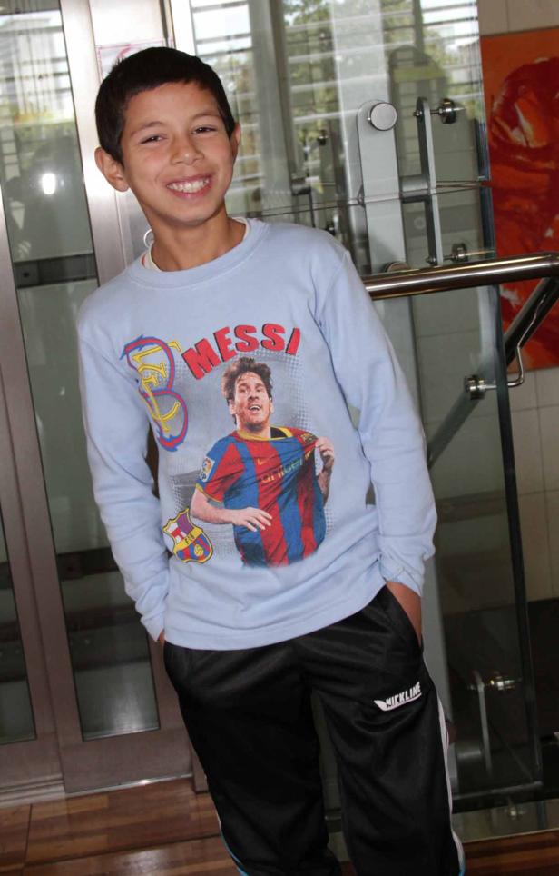Ein lächelnder Junge trägt ein Messi-T-Shirt.