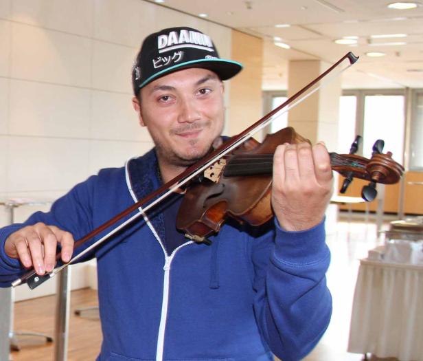 Ein Mann mit Kappe spielt auf einer Geige.