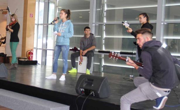 Eine Band spielt auf einer Bühne mit Geige, Gitarren, Cajón und Gesang.