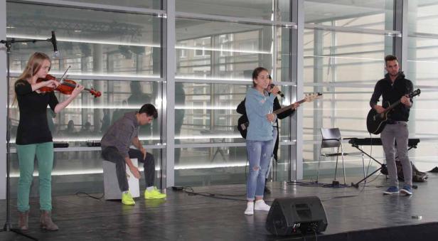 Eine Band spielt auf einer Bühne mit Geige, Gitarre und Gesang.