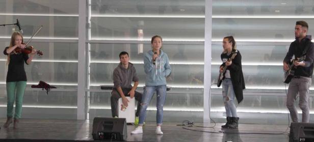 Eine Band spielt auf einer Bühne mit Geige, Cajón, Gesang, Bass und Gitarre.