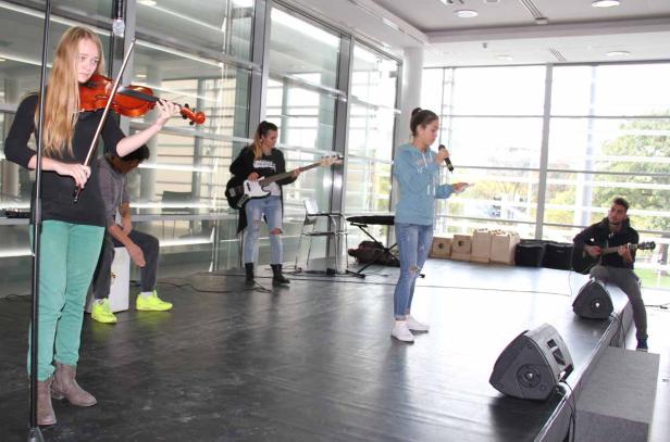 Eine junge Band spielt auf einer Bühne mit Geige, Bass, Gitarre und Gesang.