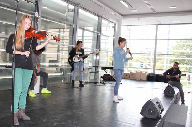 Eine Band spielt auf einer Bühne mit Geige, Gitarre, Bass und Gesang.