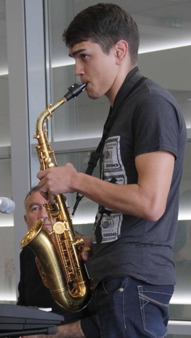 Ein junger Mann spielt Saxophon, während ein älterer Mann Klavier spielt.