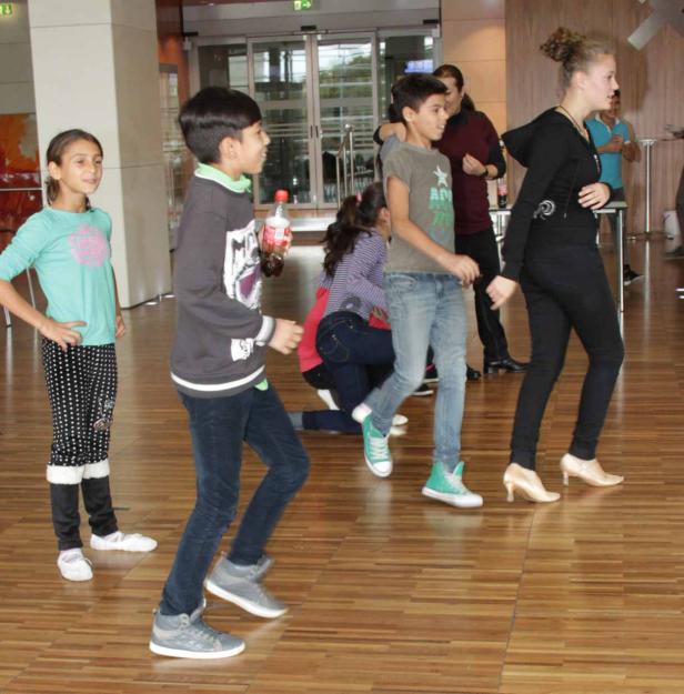 Eine Gruppe Kinder tanzt auf einem Parkettboden.