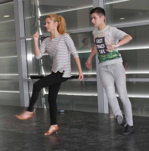 Zwei Jugendliche tanzen in einem hellen Raum.