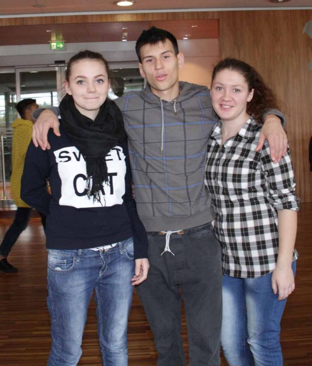 Drei junge Leute stehen nebeneinander und umarmen sich.