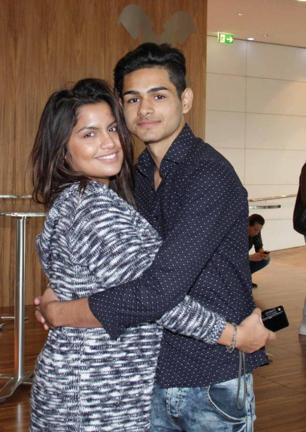 Ein junges Paar umarmt sich und lächelt in die Kamera.