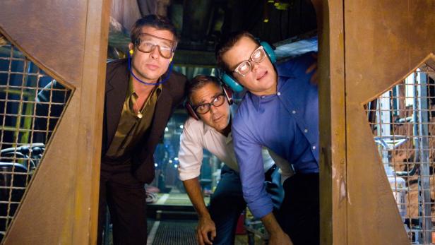 Brad Pitt, George Clooney und Matt Damon tragen Schutzbrillen und Kopfhörer.