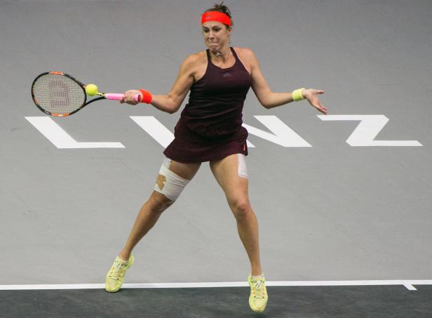 Eine Tennisspielerin mit einem roten Stirnband schlägt einen Ball.