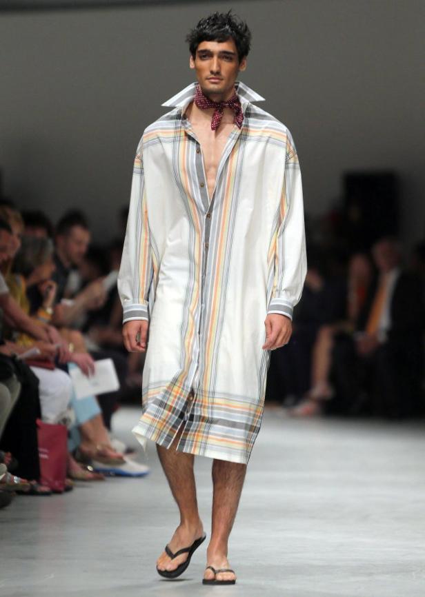 Ein Mann mit offenem Hemd und Halstuch läuft auf dem Laufsteg.